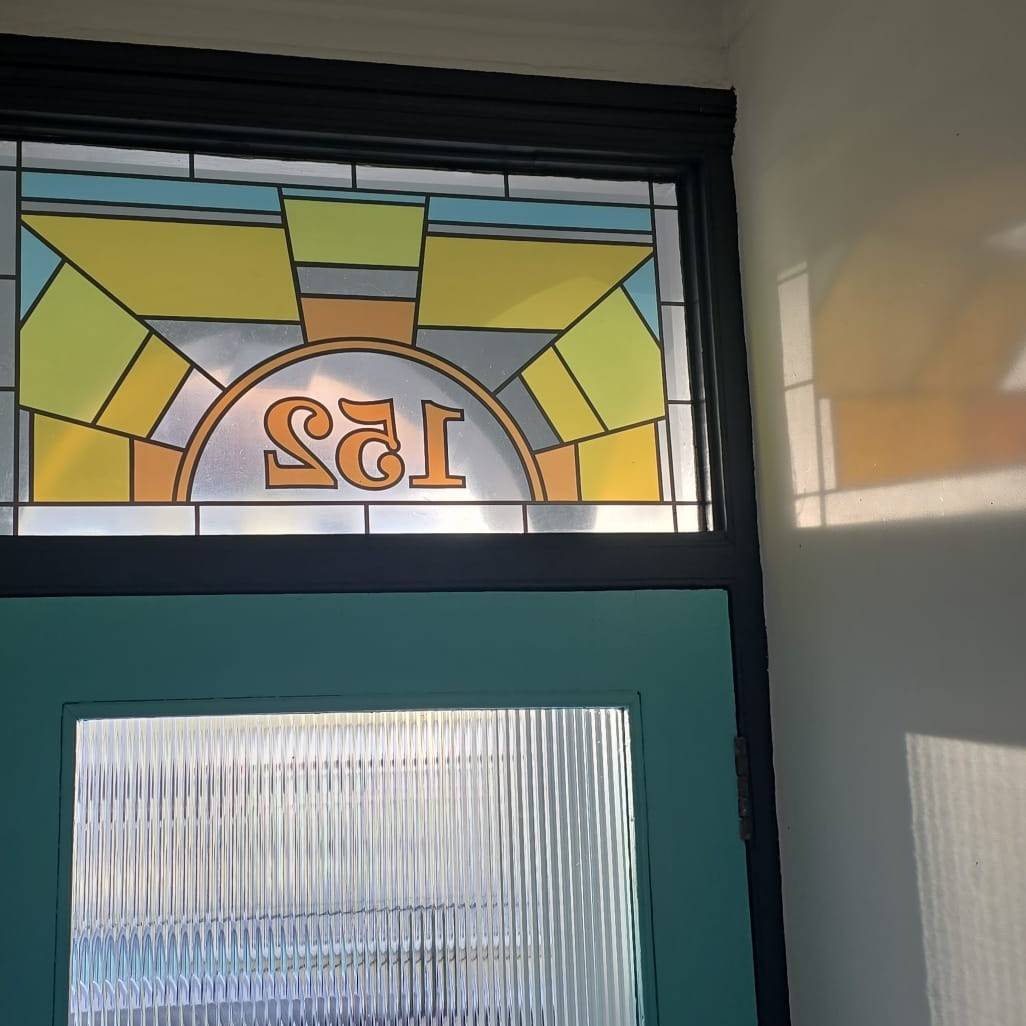 Kyoko sun stained glass window film with central door number installed above a door with reeded glass for privacy