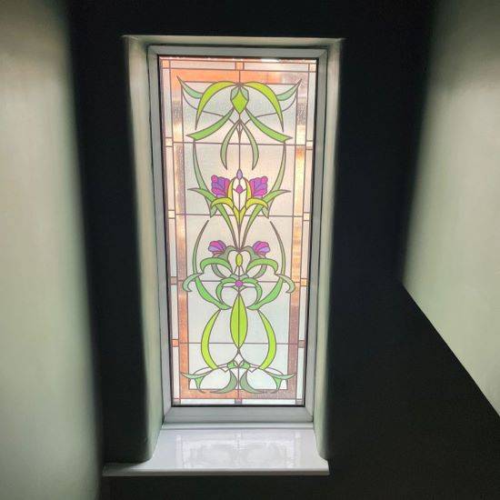 Cynthia stained glass window film in a Victorian style with purple flowers installed onto a window with walls of similar green colour to match.