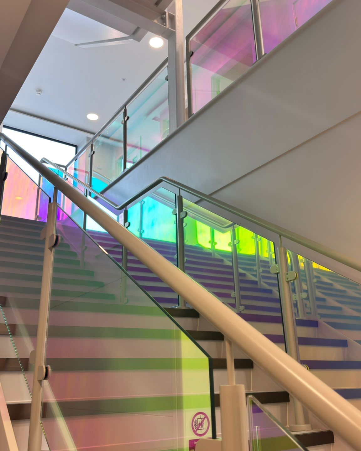 Dichroic window film, colour changing film installed on glass panels on stairs.