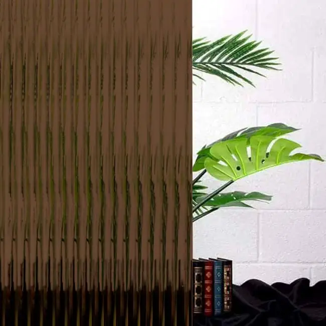 A coffee brown reeded window film in front of a plant and books.