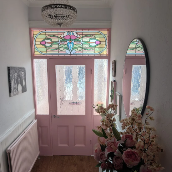 Maureen stained glass window film installed above a pink front door
