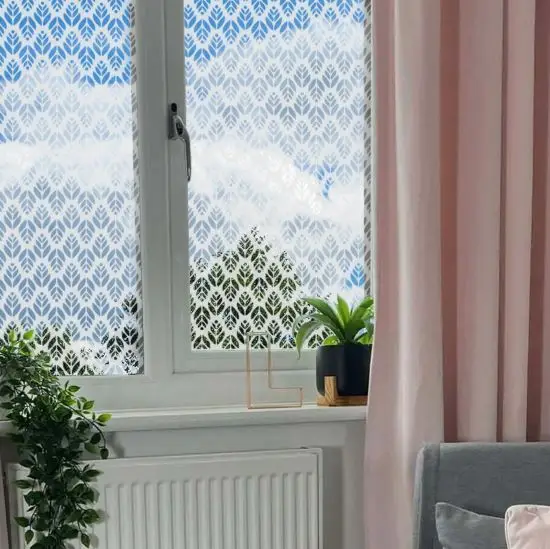 Leaf patterned frosted window film installed onto a bedroom window near two indoor plants