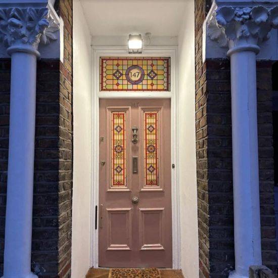 Barbara stained glass door number installed above a pink doorq