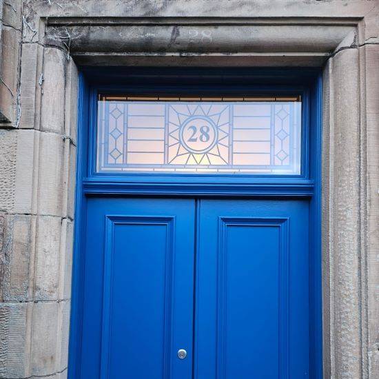 Dhani stained glass window film with a central door number installed above a blue front door