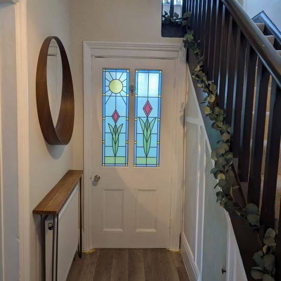 A simple stained glass window film with a central flower and a sun beaming down on one. Custom designed window film to look different.