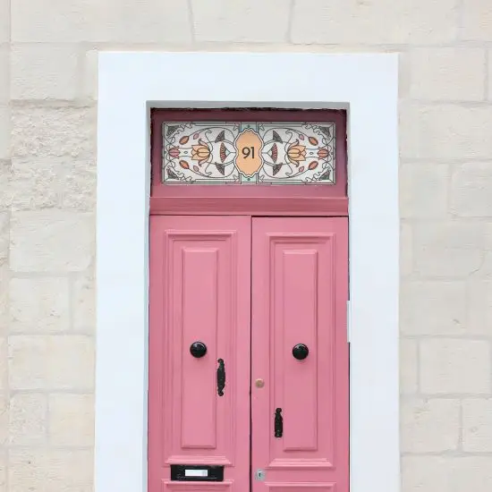 A floral stained glass window film with central door number installed above a pink door