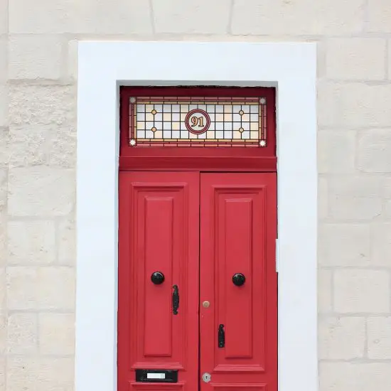 Catherine Victorian styled stained glass window film with a central door number installed above an old red door
