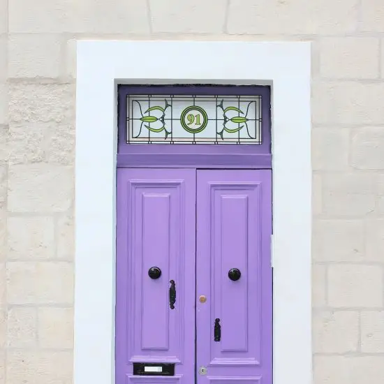 Cynthia stained glass window film with a central door number installed above a lilac door