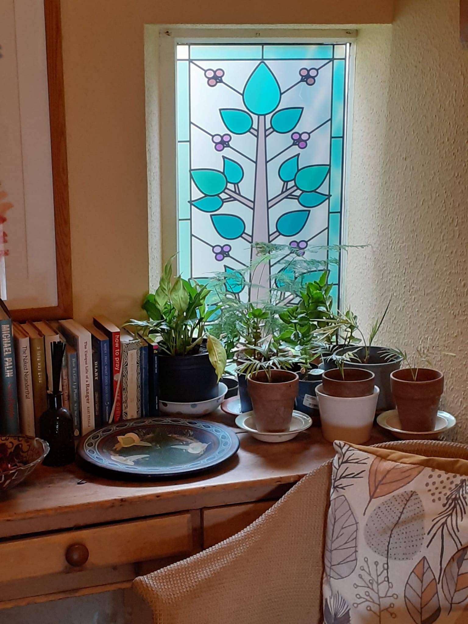 Tree stained glass window film installed on a window behind many house plants