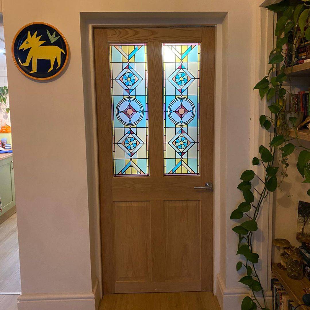 Two stained glass window films installed on an internal wooden door with glass panes