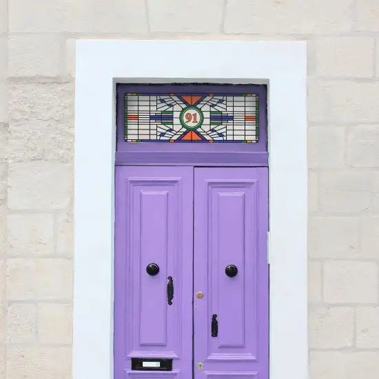 Olivia stained glass window film in a modern design with different shapes and a central house number installed above a purple front door.
