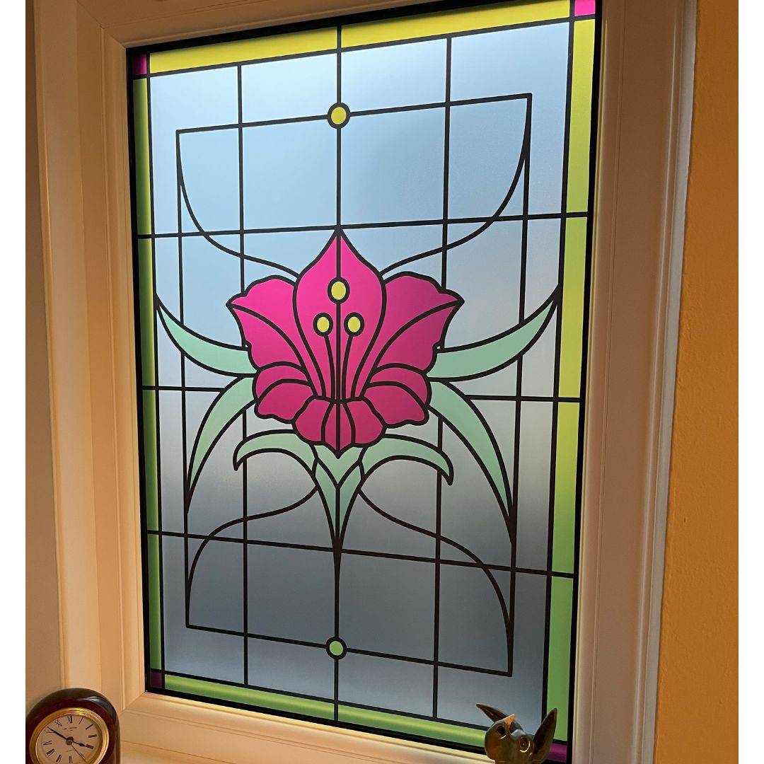 Stained glass window film in a clear finish with a center red flower and a yellow border installed onto a window