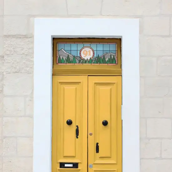 A modern stained glass door number with a blue background, mountains and trees