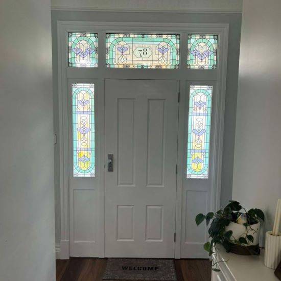Stella stained glass window film collection installed onto tall glass panels and wide glass panels around a front door.